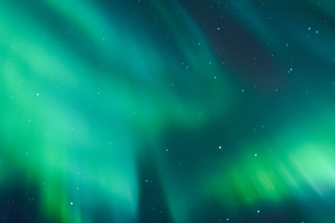 Green northern lights glowing across a starry night sky in Iceland.