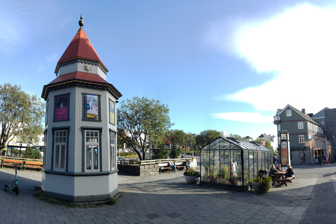 Small historic tower and greenhouse in a sunny square in downtown Reykjavík.