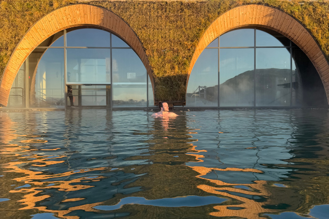 Visitor enjoying the warm geothermal waters at Laugarás Lagoon during sunset.