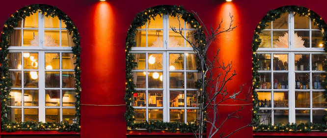 Warmly lit restaurant windows decorated with Christmas lights and garlands on a red building in Reykjavík.