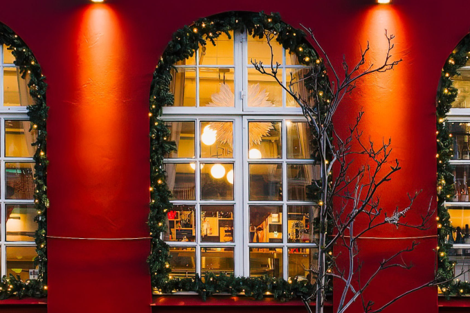Warmly lit restaurant windows decorated with Christmas lights and garlands on a red building in Reykjavík.