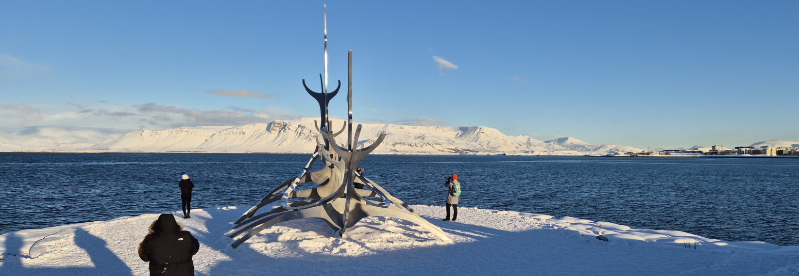 Sun Voyager sculpture in Reykjavík in winter with snow, ocean views, and mountains in the background