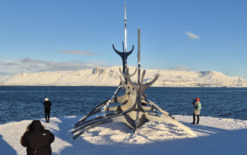 Sun Voyager sculpture in Reykjavík in winter with snow, ocean views, and mountains in the background
