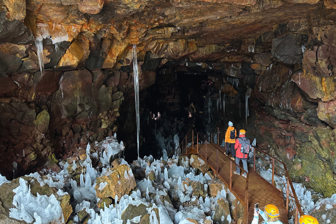 Visitors exploring an Icelandic lava cave with ice formations during winter