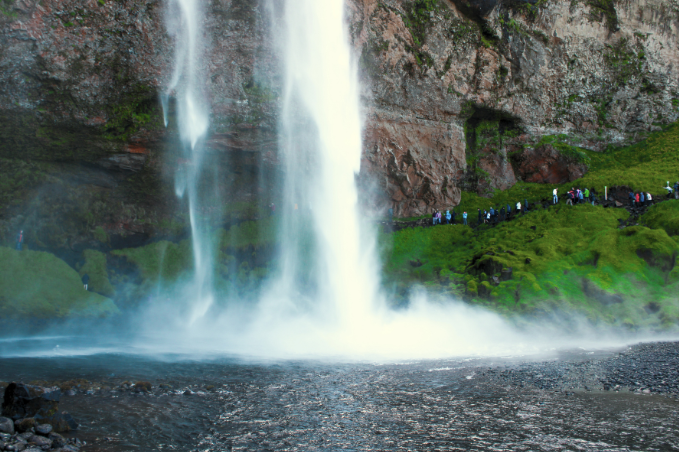 Visitors walking behind Seljalandsfoss waterfall in South Iceland