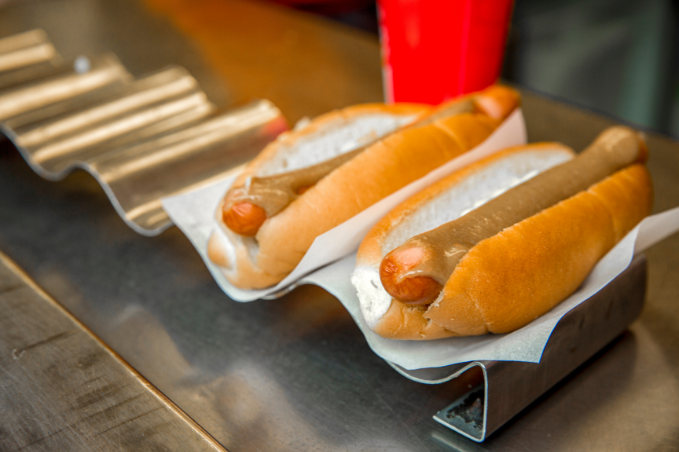 Two Icelandic hot togs with mustard in buns served on a metal tray in Reykjavik, Iceland.