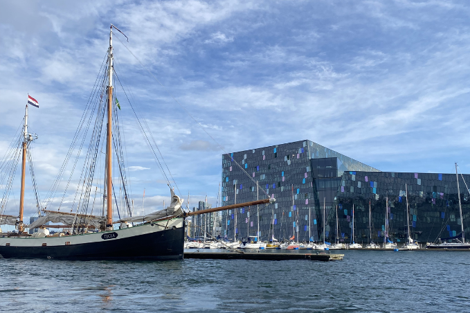 Traditional sailing boat moored in Reykjavík Old Harbour with Harpa Concert Hall in the background.