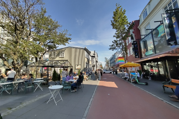 People enjoying cafés and shops along Laugavegur, Reykjavík's main shopping street on a sunny day.
