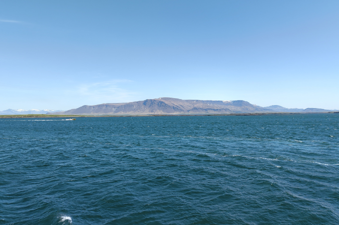 Scenic view across Faxaflói Bay with Icelandic mountains under a clear blue sky.