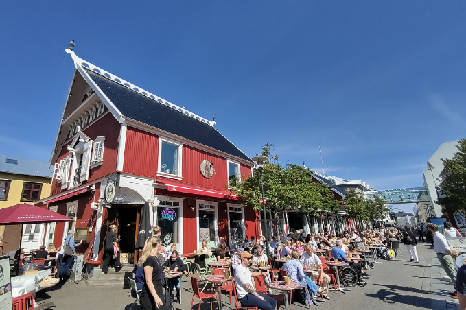Busy outdoor cafés and restaurants along Ingolfstorg square in Reykjavík on a sunny summer day.