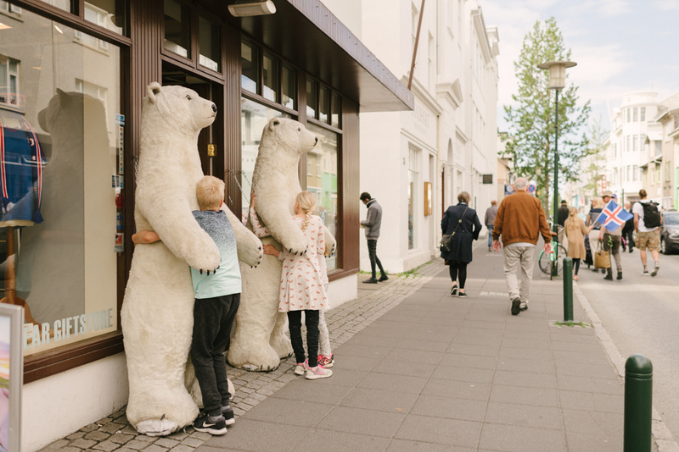 Stuffed fake polar bears being hugged by two children on laugavegur shopping street in reykjavik city center