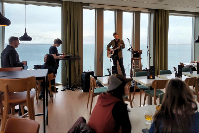 Musician performing live acoustic music inside a SKÝ Lounge & Bar overlooking the ocean