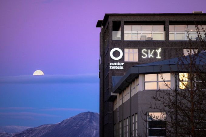 View of Center Hotels Arnarhvoll building with Reykjavík skyline and mountains during sunset