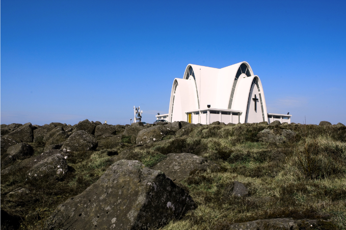 church surrounded by lava rocks under a clear blue sky in Kopavogur