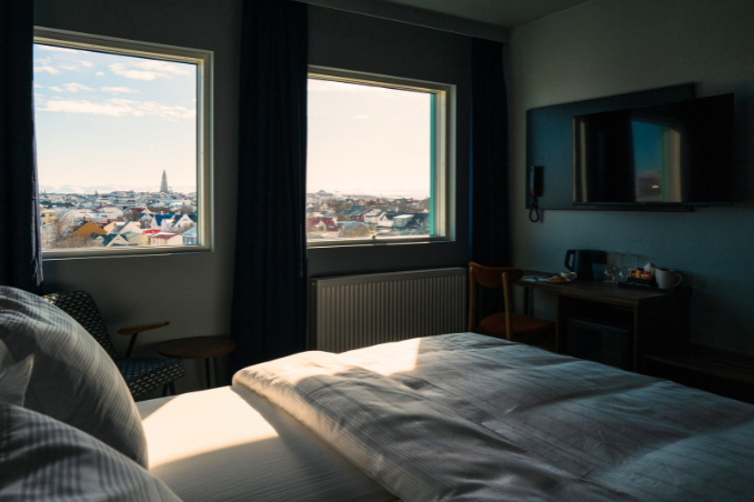 Bright hotel room in Reykjavík with panoramic city views through large windows