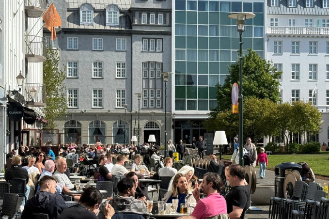 People enjoying drinks and outdoor dining at a busy square in downtown Reykjavík