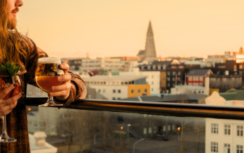 Couple enjoying cocktails on a rooftop bar in Reykjavík during sunset with city skyline views