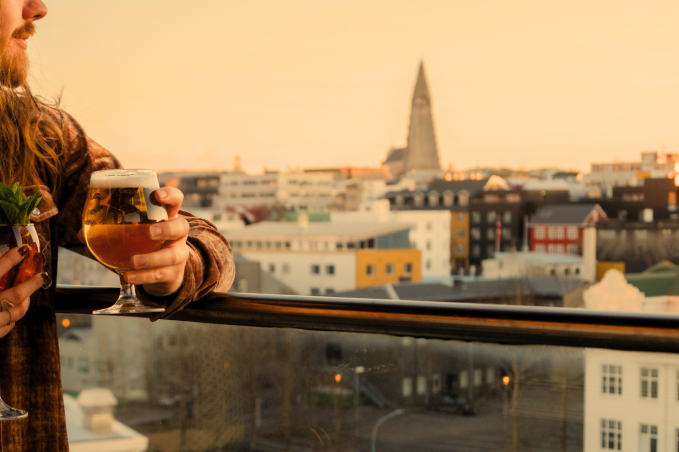 Couple enjoying cocktails on a rooftop bar in Reykjavík during sunset with city skyline views