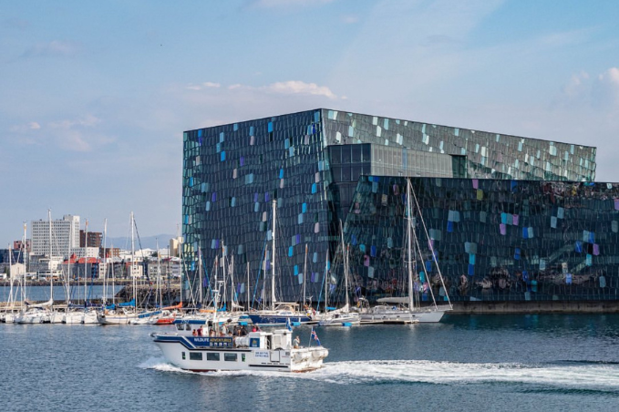 Harpa Concert hall in Reykjavik with boats and marina in the foreground.