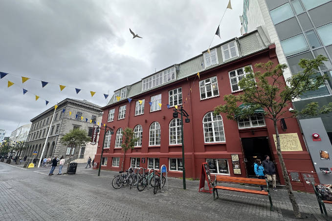 Colorful street in Reykjavík with red building, bicycles, and people walking