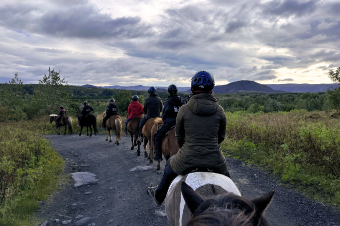 Group of people riding Icelandic horses along a scenic countryside trail