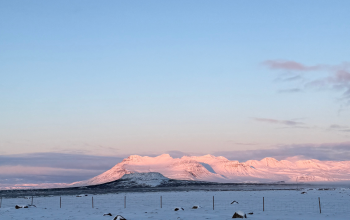 Snow-covered mountains in Iceland glowing in soft sunset light during winter