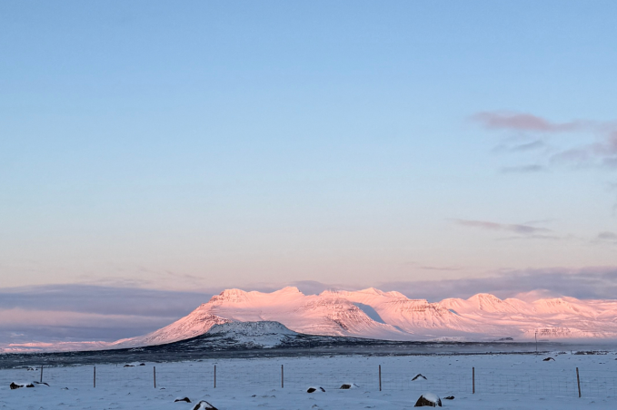 Snow-covered mountains in Iceland glowing in soft sunset light during winter