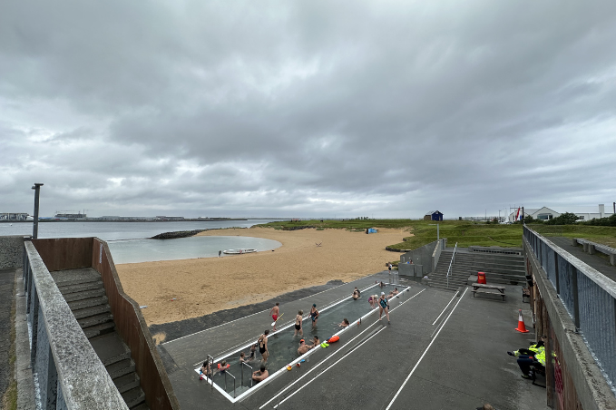 People relaxing in a seaside geothermal pool near Reykjavík on a cloudy day
