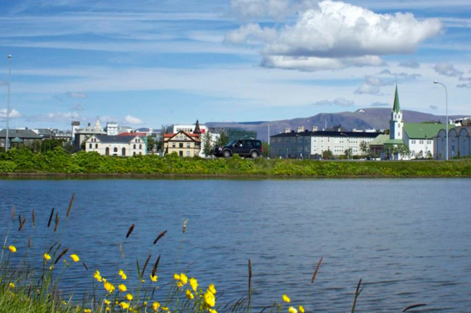 The "Tjörnin" or the Reykjavik pond during the summertime. An overview over the pond with buildings visible at the end of the pond.