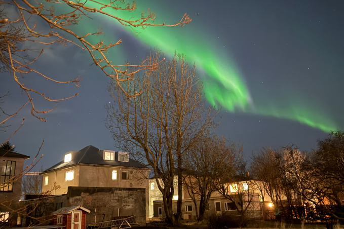 Green Northern Lights glowing above Reykjavík at night.