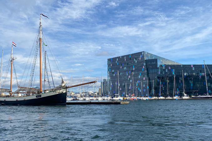 Harpa Concert Hall by Reykjavík harbour with a sailing ship in the foreground