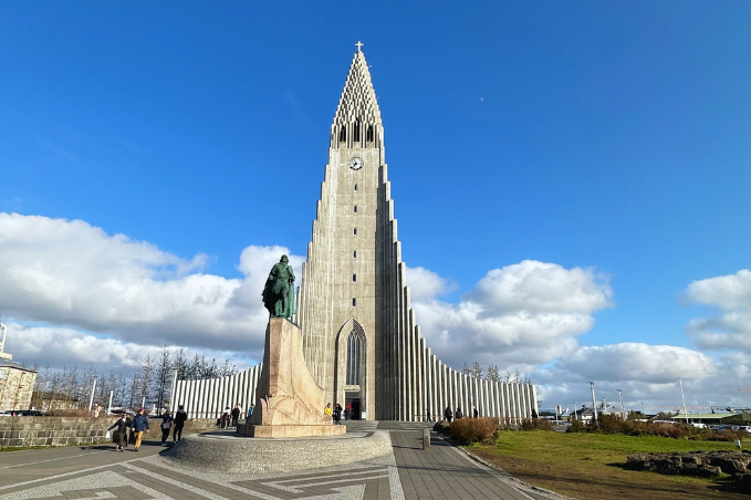 Hallgrímskirkja church and Leif Erikson statue in central Reykjavík under a blue sky.